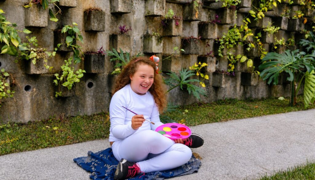 Stella Moraes, artista mirim com Síndrome de Down e autismo, pintando em sua exposição 'Sonho e Cores' em Niterói.