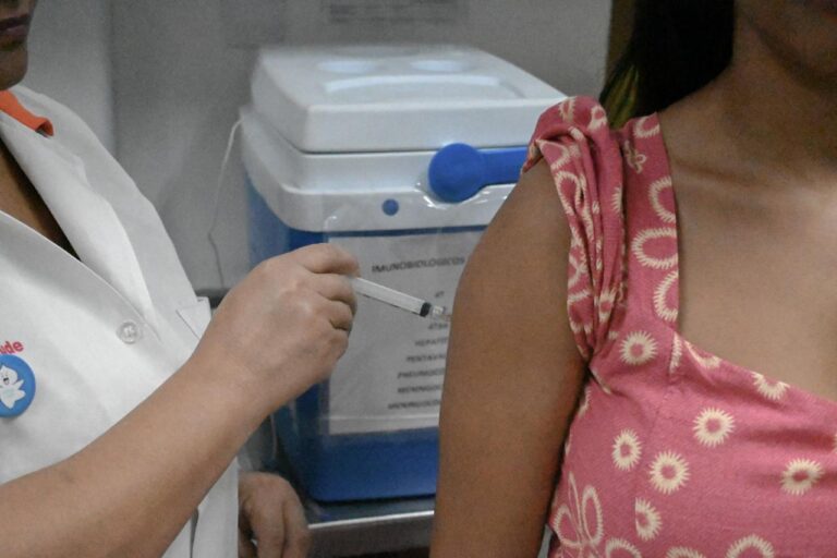Adolescente recebendo vacina contra HPV em unidade de saúde de Niterói, com profissional de saúde aplicando a dose.