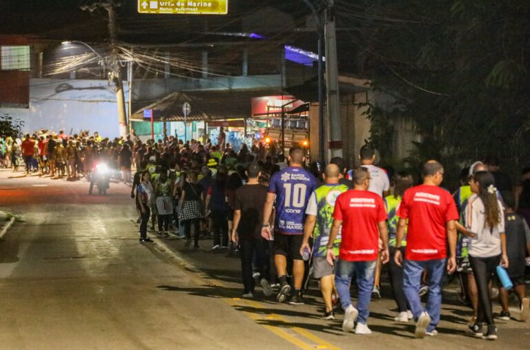 Participantes em caminhada noturna com iluminação rosa em Maricá, Outubro Rosa.