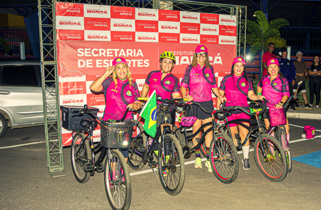 Ciclistas em pedalada noturna iluminada em Maricá, conscientização Outubro Rosa.