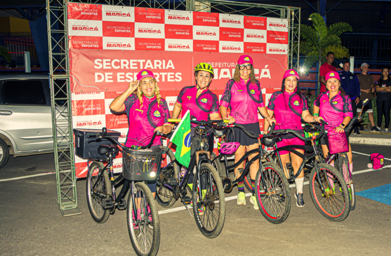 Ciclistas em pedalada noturna iluminada em Maricá, conscientização Outubro Rosa.