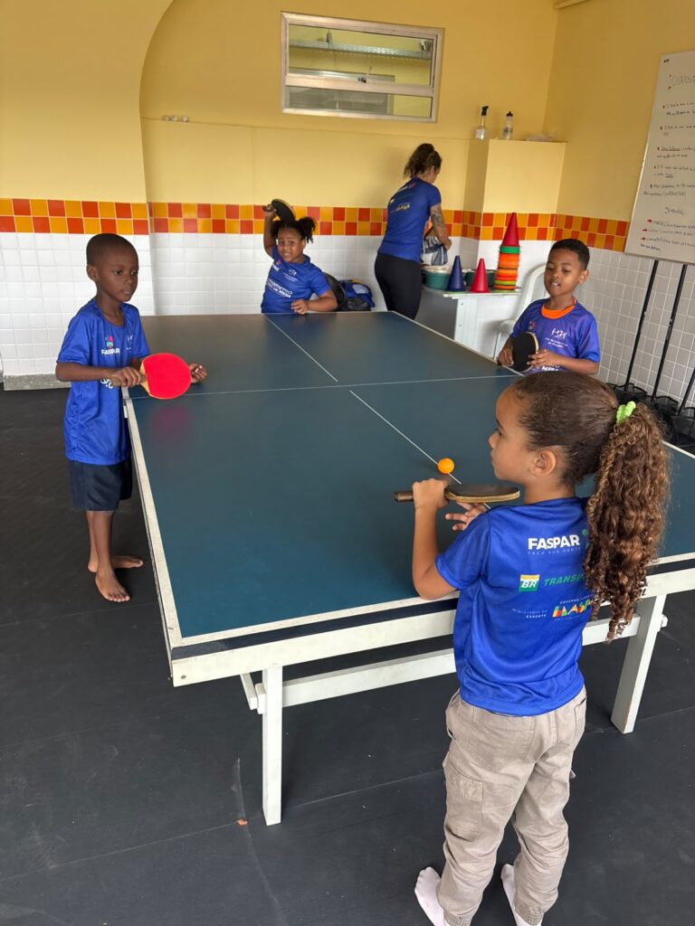 Jovens jogando tênis de mesa em Niterói, projeto gratuito da Prefeitura e Transpetro para inclusão social.