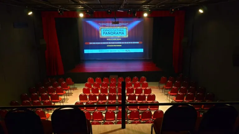 Pessoas em frente ao Espaço Cultural Panorama, em São Gonçalo, com livros e equipamentos de cinema, representando o novo corredor cultural.