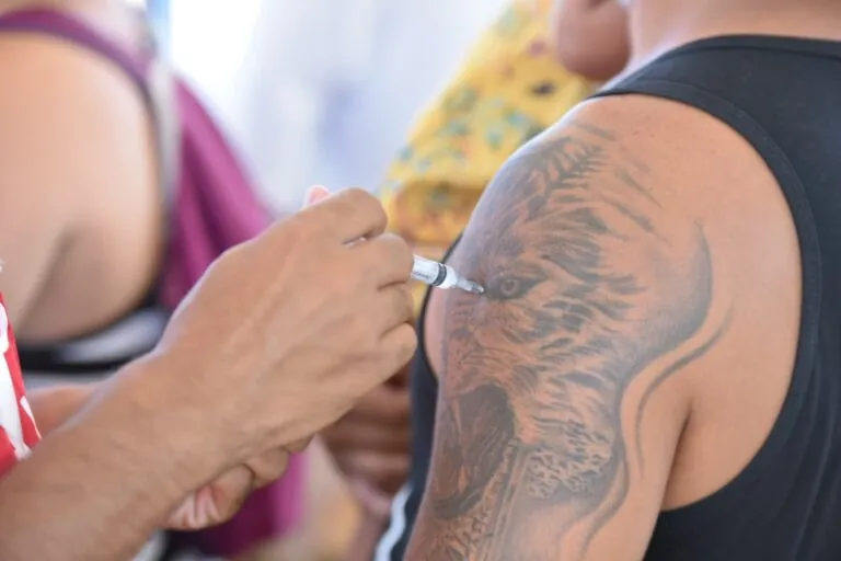 Morador de Maricá sendo vacinado contra a gripe por profissional de saúde. Ação da Prefeitura na cidade.