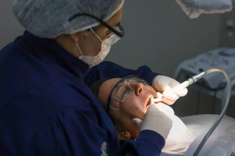 Dentista realizando tratamento de canal em paciente durante mutirão em Maricá.