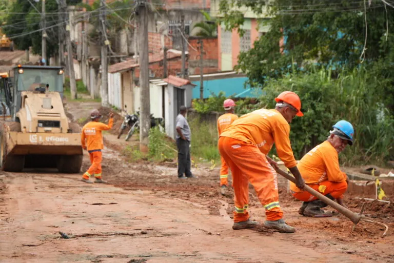 Máquinas trabalham em obras de pavimentação e drenagem em rua de São Gonçalo, com foco em acessibilidade e urbanização.