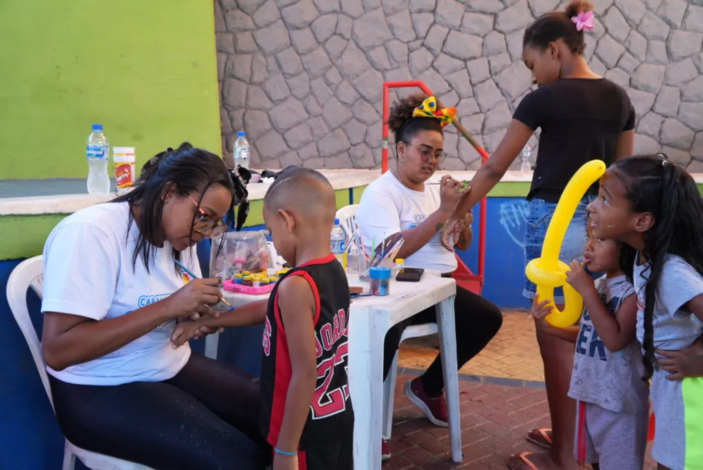 Crianças brincando em brinquedos infláveis da Caravana de Arte e Lazer em São Gonçalo, com monitores.
