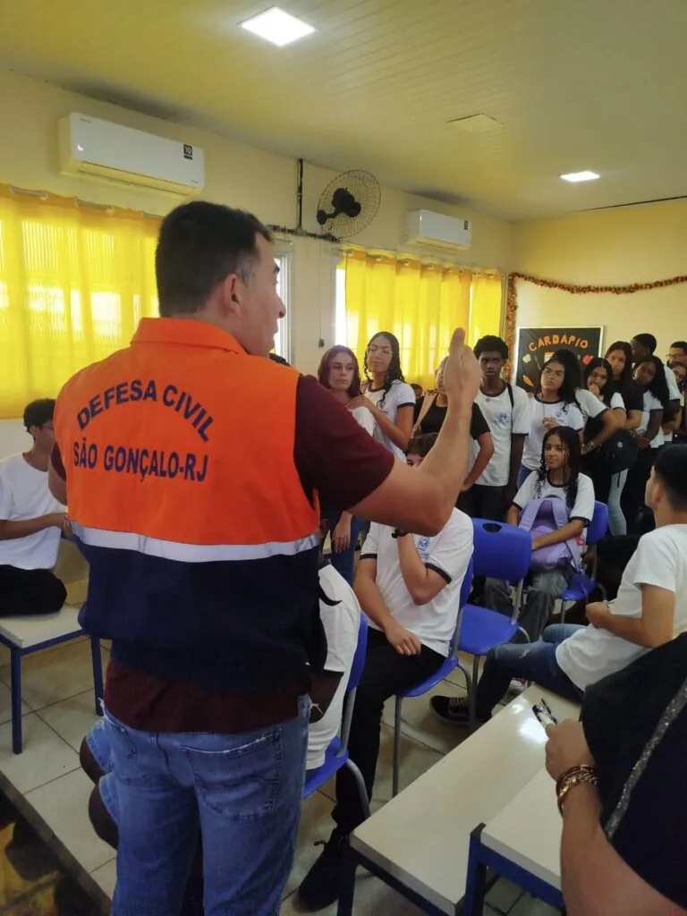 Agentes da Defesa Civil de São Gonçalo palestram para estudantes em sala de aula sobre prevenção de riscos.