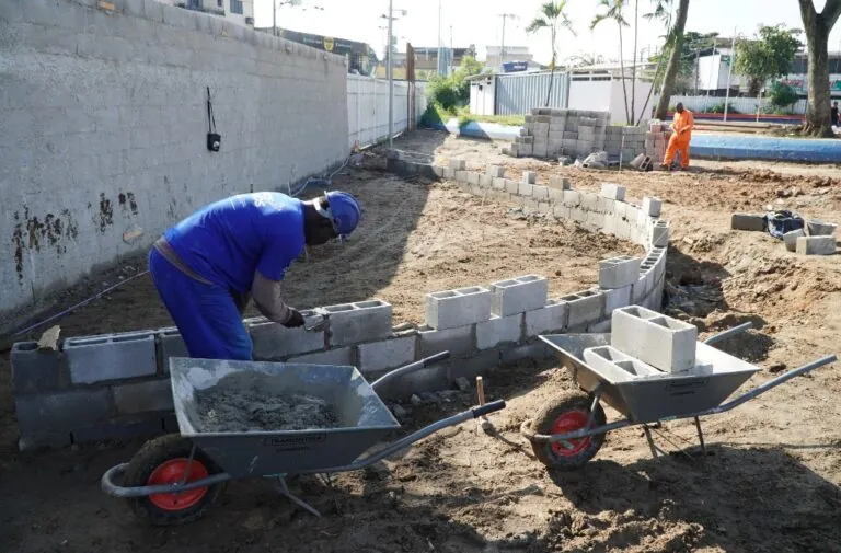 Trabalhadores instalam novo piso drenante na Praça da Trindade em São Gonçalo, parte da reforma e modernização do espaço.