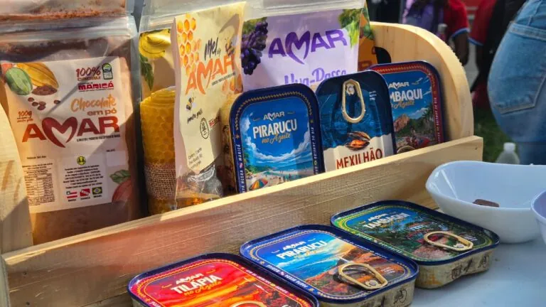 Moradores de Maricá em feira de agricultura familiar, com produtos frescos em exposição, durante projeto da AMAR.