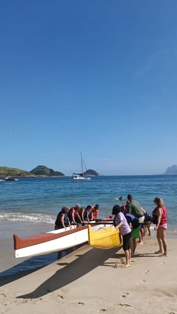 Pessoas em canoa havaiana com instrutor, simbolizando inclusão no esporte em Niterói.