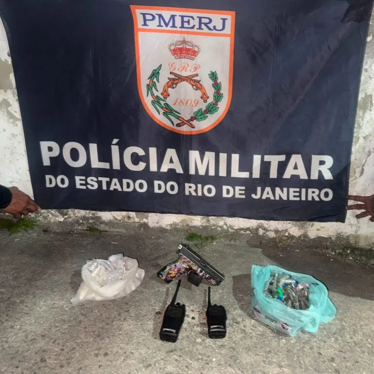 Policiais militares exibem pistola, rádios e drogas apreendidos após prisão em São Gonçalo.