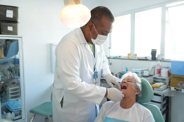 Paciente idosa sorri após receber prótese dentária gratuita pelo SUS em São Gonçalo.