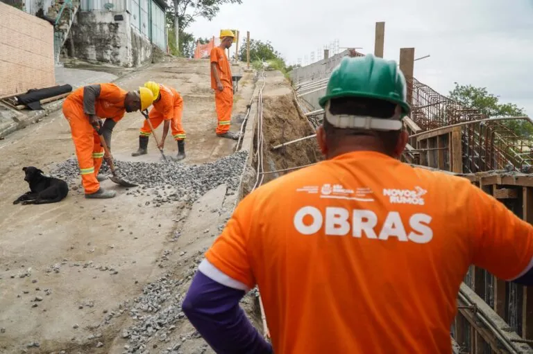 Obras de contenção e drenagem na Rua Vinte e Sete de Julho, no Lindo Parque, em São Gonçalo, com operários e máquinas.