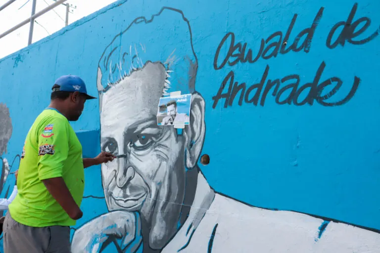 Mural artístico colorido no corredor viário do MUVI em São Gonçalo, retratando o Palacete do Mimi e artistas famosos.