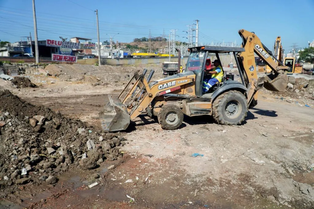 Obras do MUVI em São Gonçalo com máquinas e trabalhadores na Rua Adelaide Lima, Jardim Catarina, construindo ciclovia e calçada.