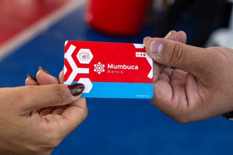Pessoas utilizando a moeda social Mumbuca em comércios de Maricá, RJ, celebrando seus 13 anos de existência.
