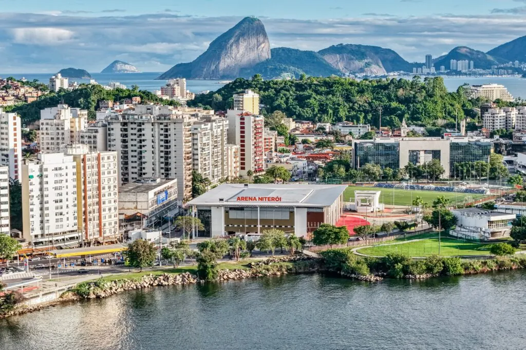 Vista interna da Arena Niterói pronta para receber evento esportivo com arquibancadas e quadra ao centro.